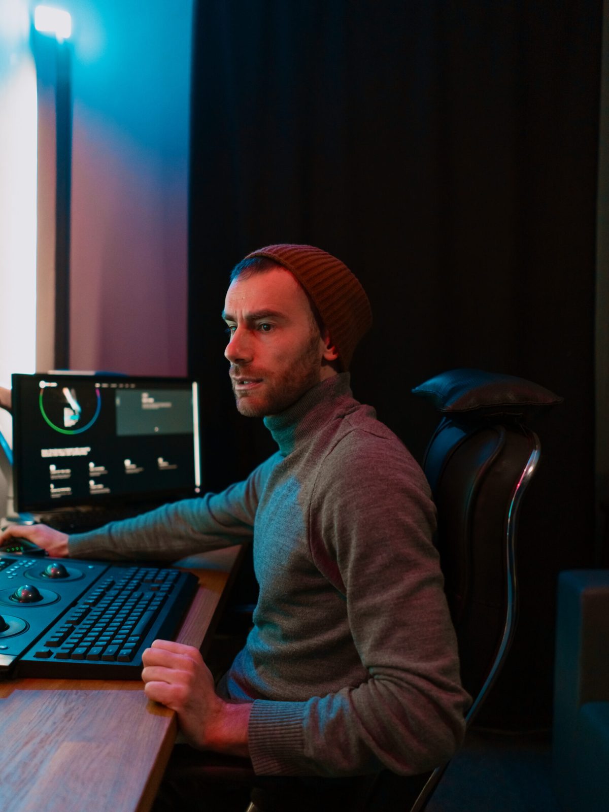 Attractive Male Video Editor Works with Footage or Video on His Personal Computer, he Works in Creative Office Studio or home. Neon lights
