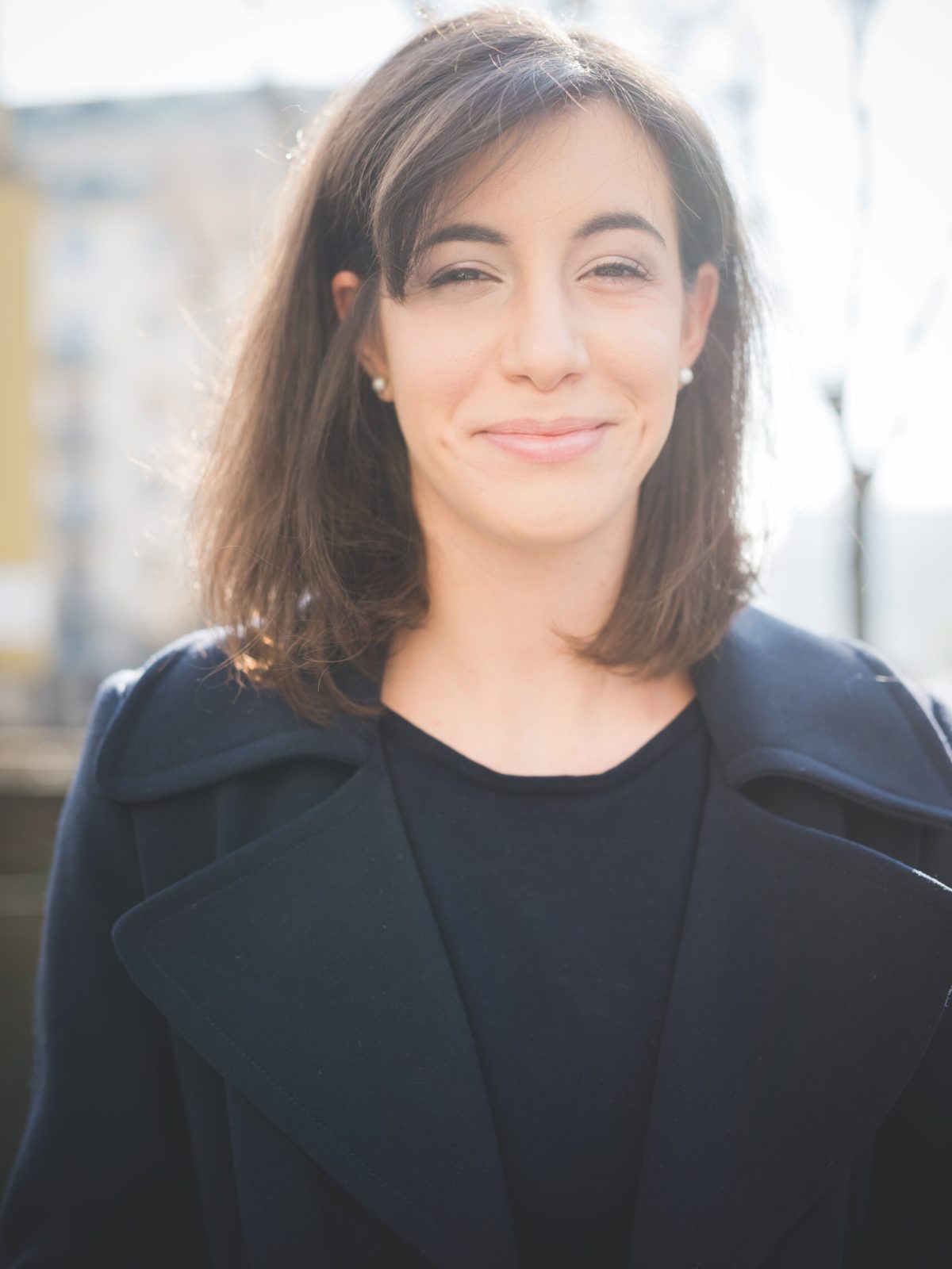 Half length of a young pretty brown hair caucasian girl looking in camera, dressing a black coat and a black shirt - relax, happiness, carefreeness concept